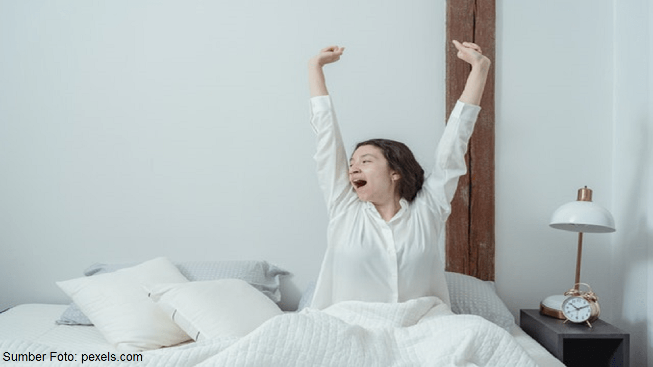 wanita sedang meregangkan tubuh dengan yoga ringan di kamar tidurnya sebelum tidur untuk relaksasi