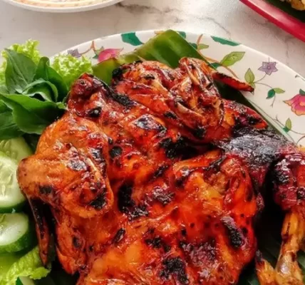 Ayam panggang madu berwarna kecokelatan mengilap, disajikan dengan taburan biji wijen dan irisan daun bawang