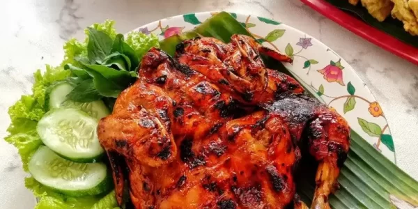 Ayam panggang madu berwarna kecokelatan mengilap, disajikan dengan taburan biji wijen dan irisan daun bawang