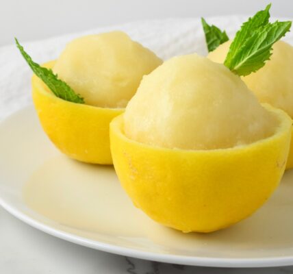 Sorbet lemon berwarna cerah tersaji dalam mangkuk, dihiasi daun mint segar untuk tampilan yang menggoda