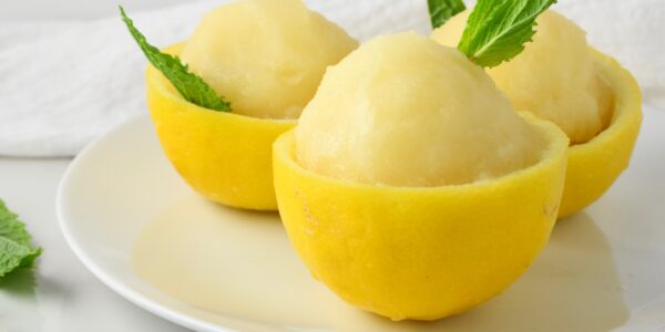 Sorbet lemon berwarna cerah tersaji dalam mangkuk, dihiasi daun mint segar untuk tampilan yang menggoda